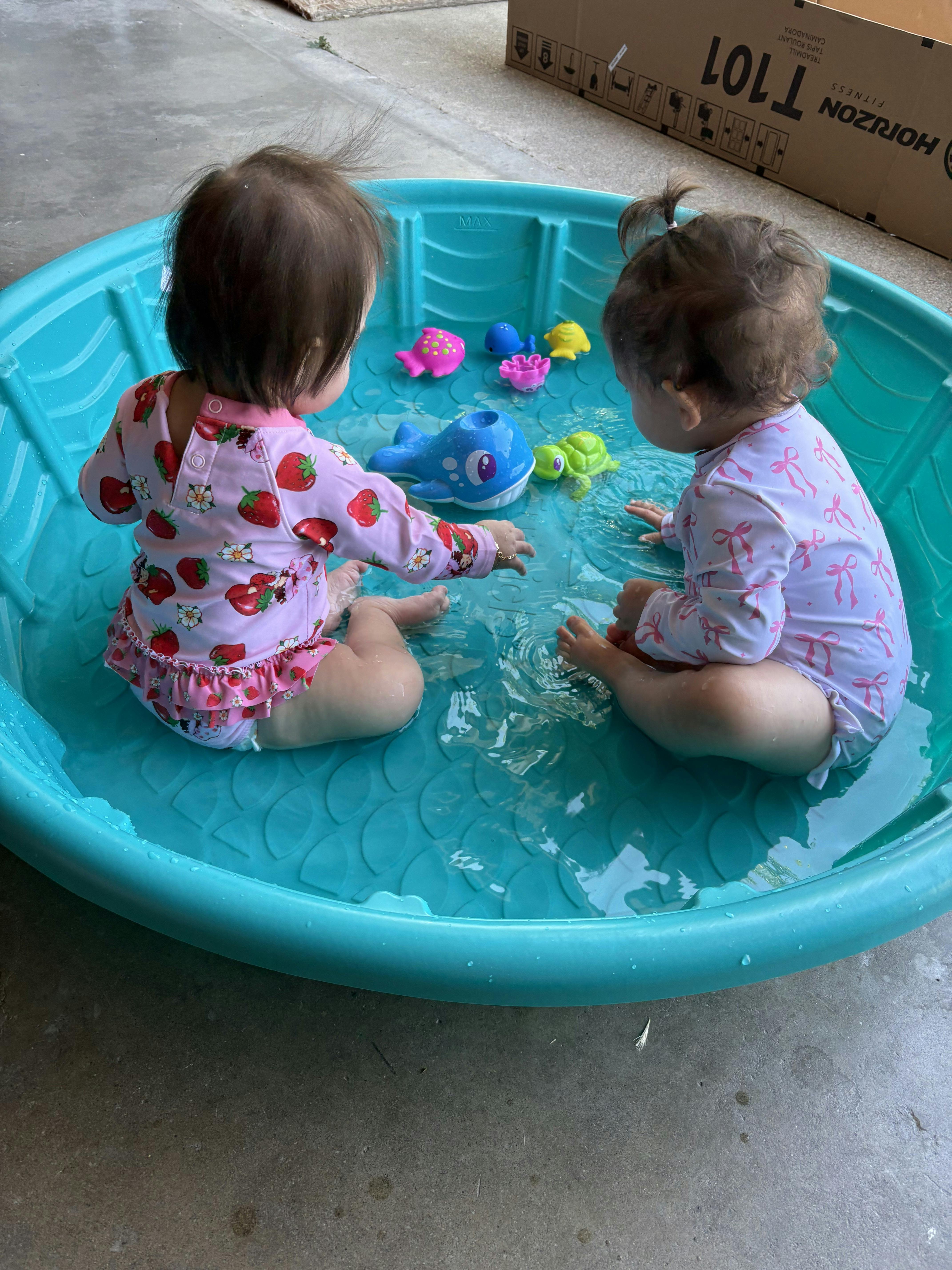 Two children playing with toys in a small wading pool
