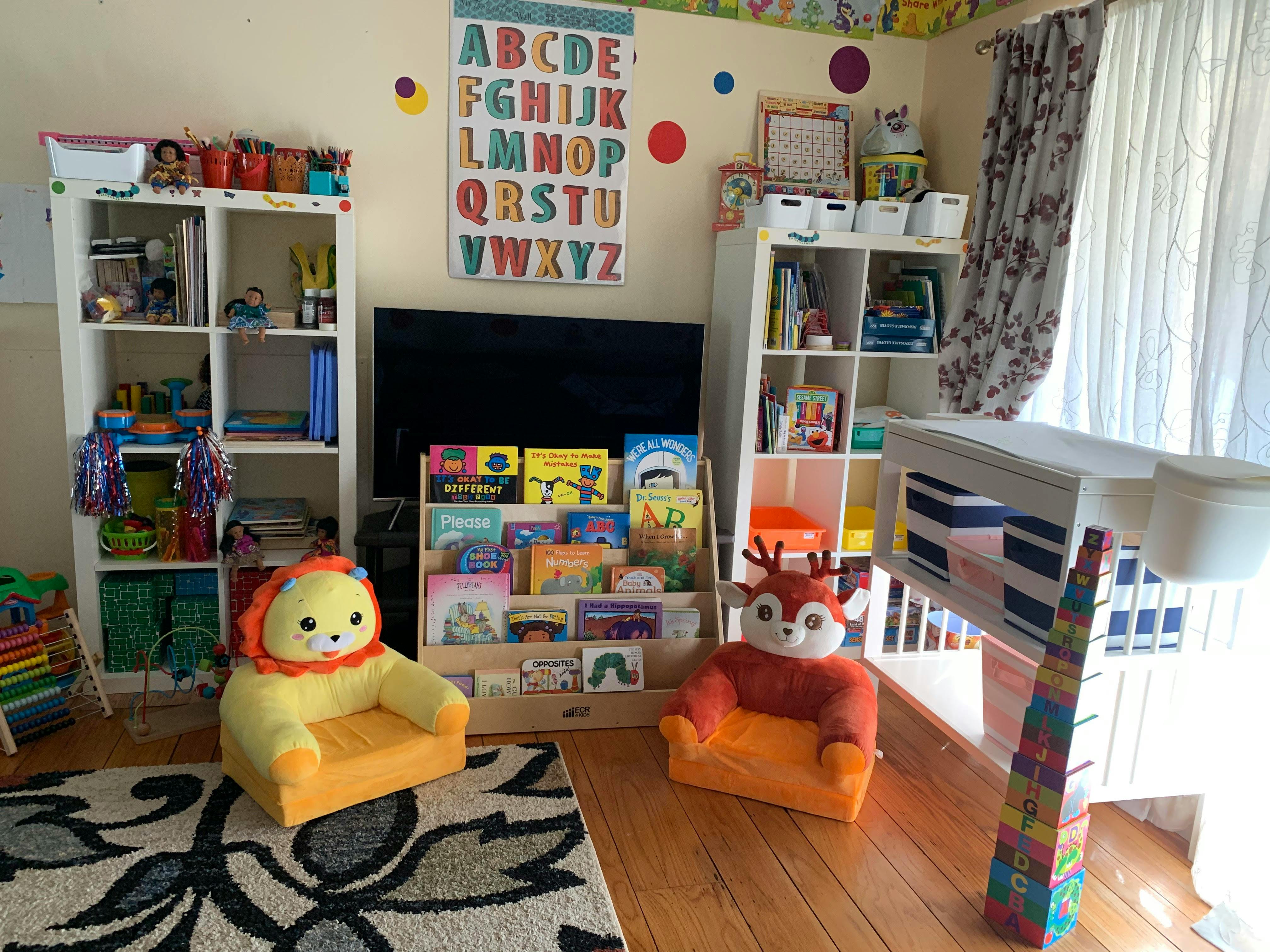 Children's playroom with bookshelves, toy chairs, and an alphabet chart