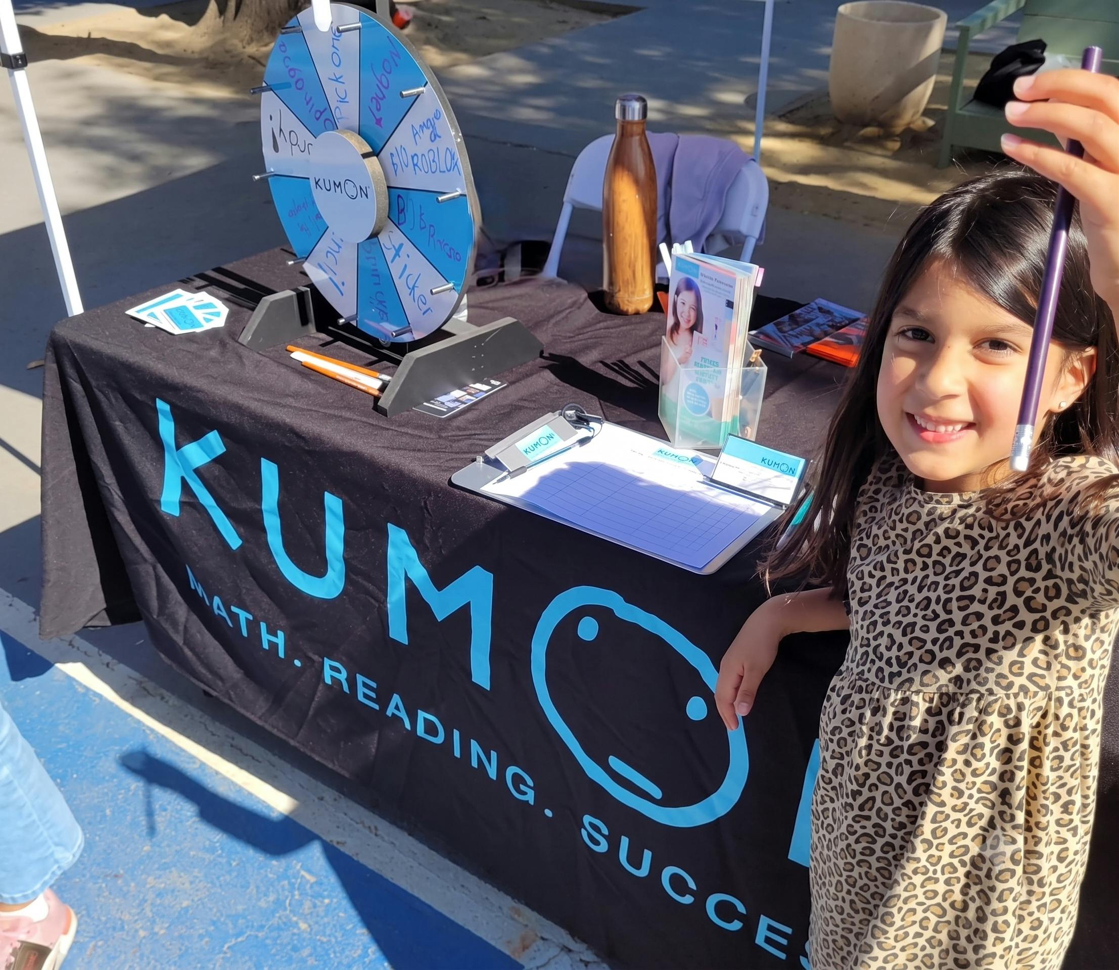 Child standing at a Kumon table with a prize wheel