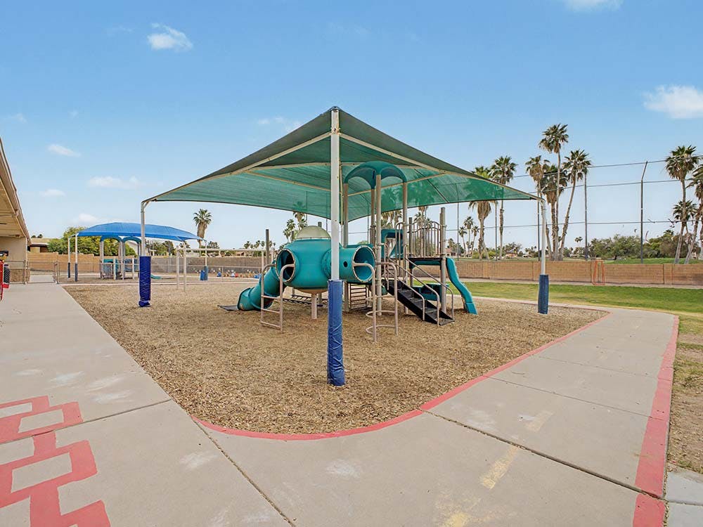 Playground with blue and green equipment under a sunshade