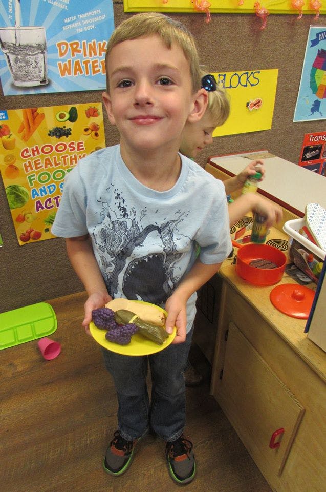 Child holding a plate with toy food