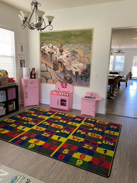 Playroom with pink toy kitchen set and colorful alphabet rug
