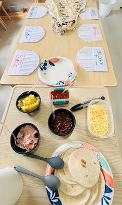 Table set with taco ingredients and paper plates