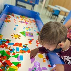 Child playing with colorful shapes on a light table