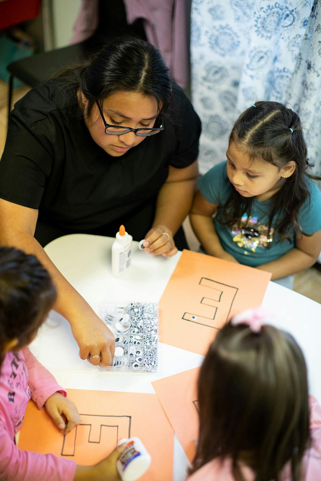Person and two children doing crafts at a table