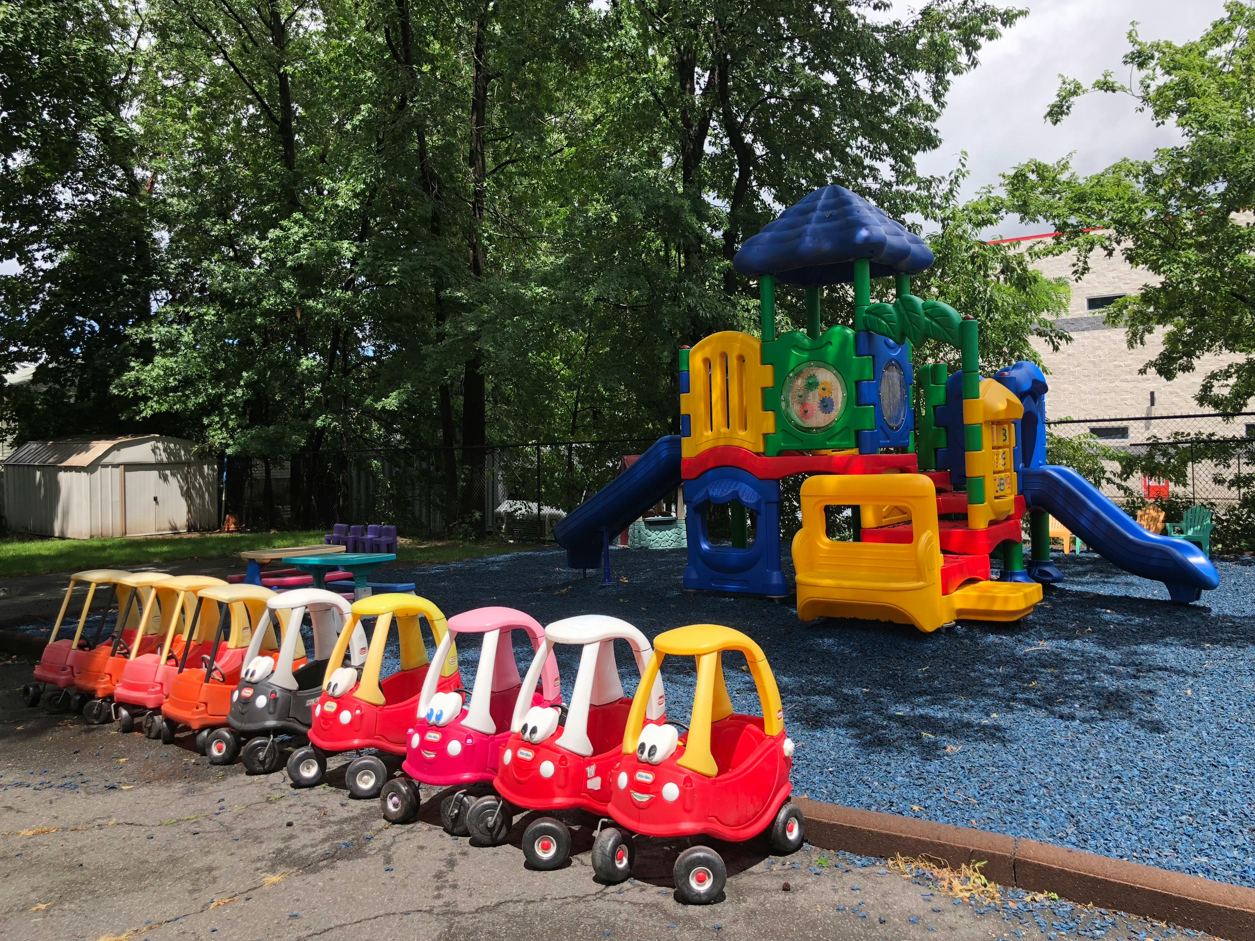 Row of toy cars next to a colorful playground structure