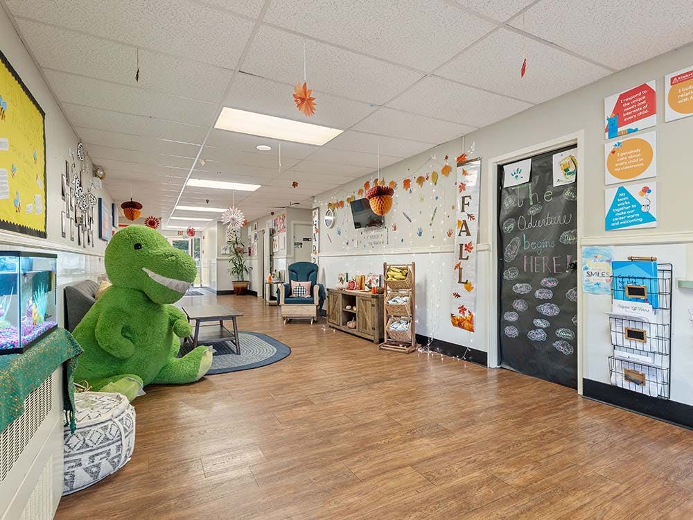 Hallway in a childcare center with a large green dinosaur plushie