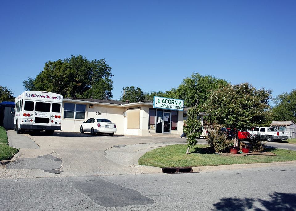 Building with "Acorn Children's Center" sign, bus, and cars outside