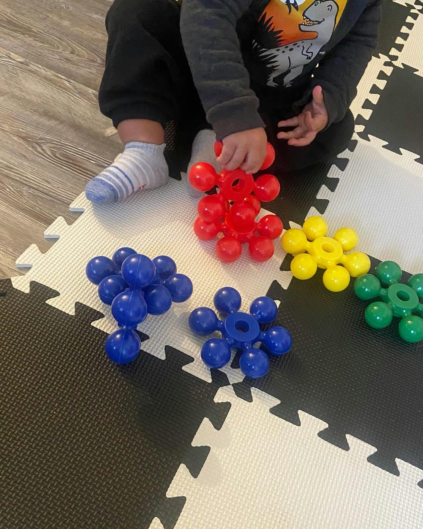 Child playing with colorful interlocking toys on a mat