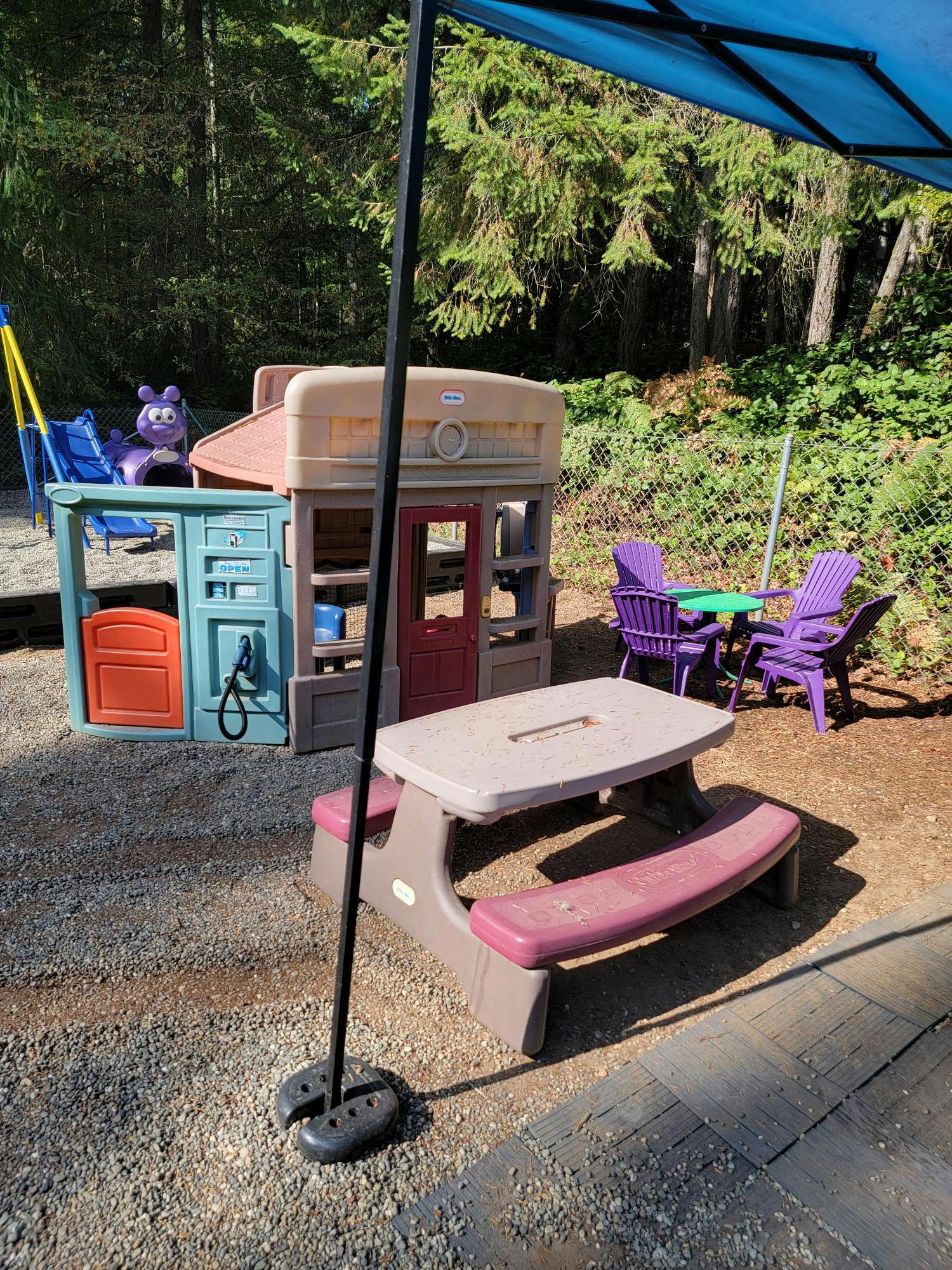Outdoor play area with a playhouse, picnic table, and chairs