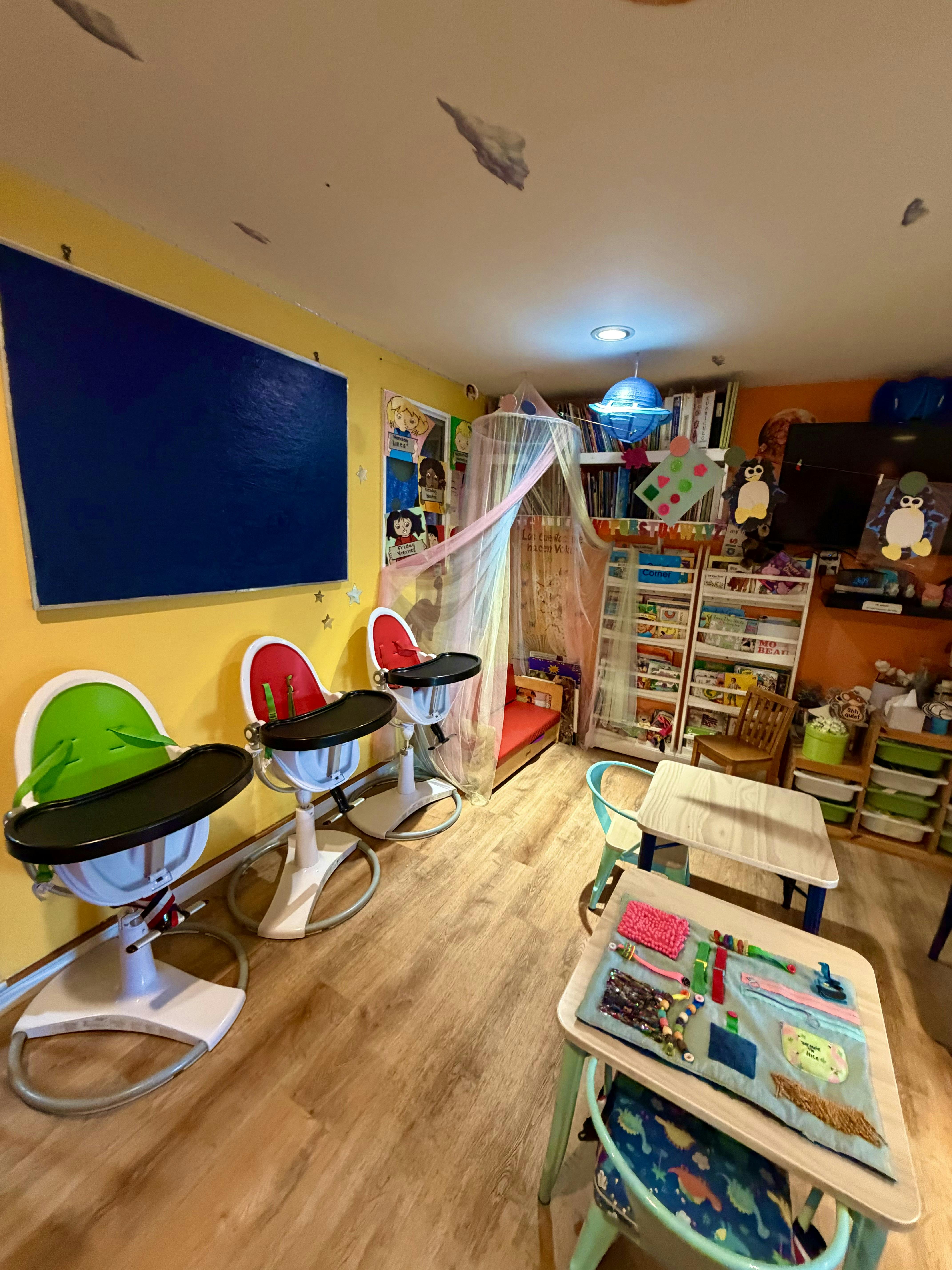 Childcare room with high chairs, small tables, and bookshelves