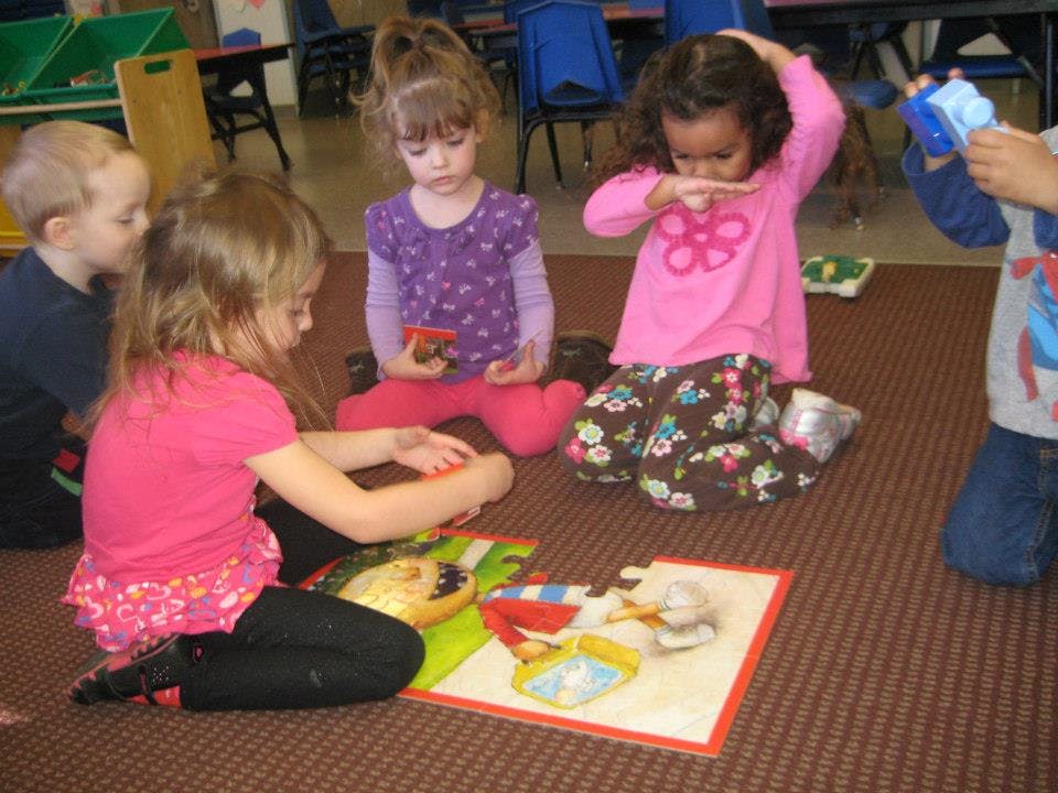 Children playing with toys on the floor in a classroom