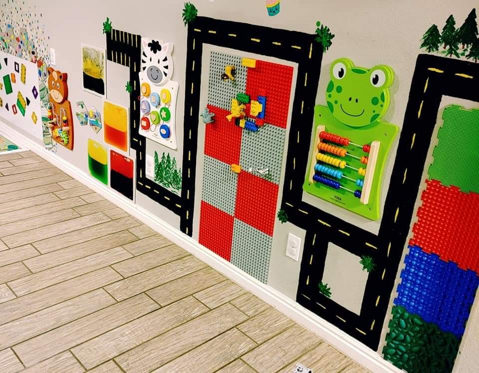 Wall with various interactive play panels, including a frog abacus and building blocks