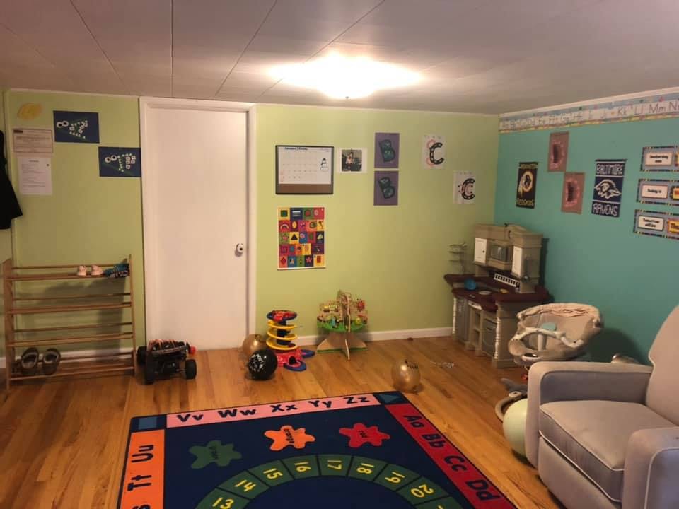 Room with light green and blue walls, a colorful rug, and various toys