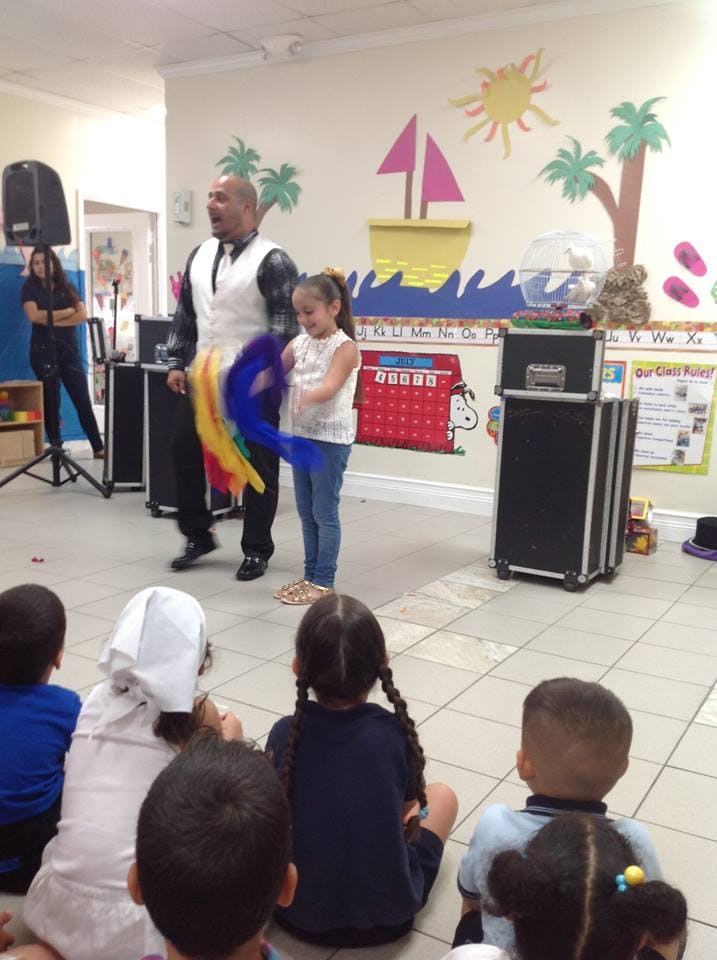 Person performing magic with a child in front of seated children