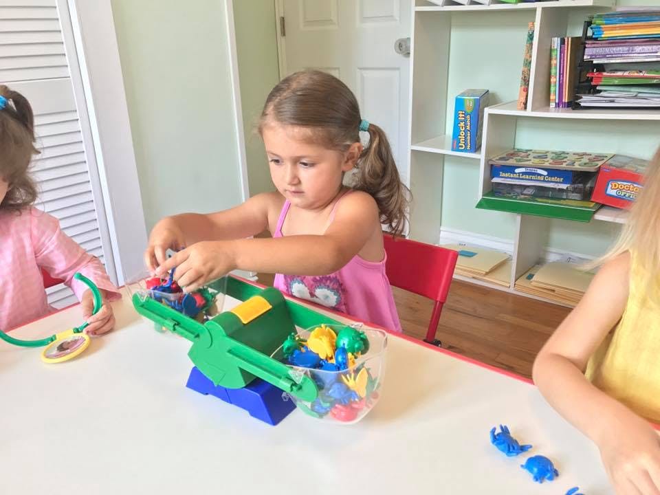 Child playing with a toy scale at a table