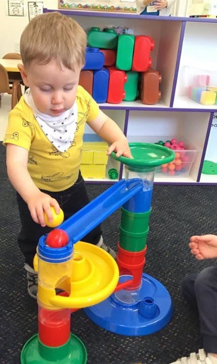 Child playing with a colorful ball run toy
