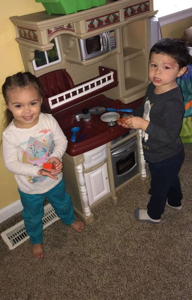 Two children playing with a toy kitchen