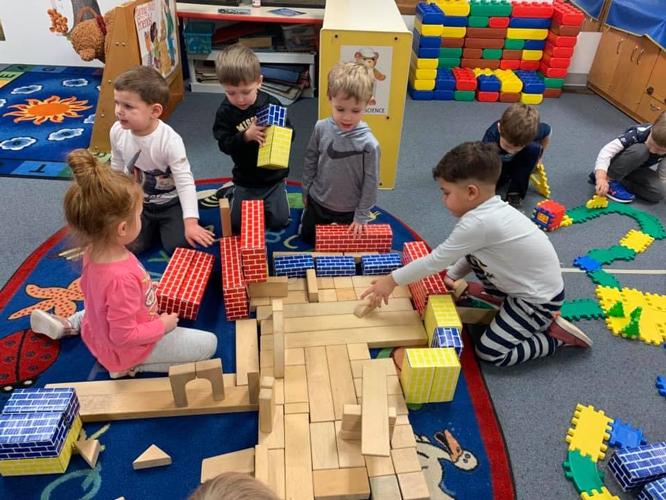 Children playing with blocks on a rug in a classroom