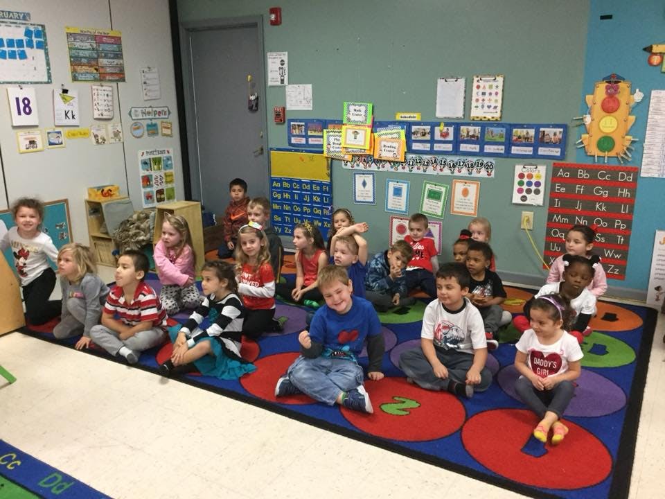 Children sitting on a colorful rug in a classroom