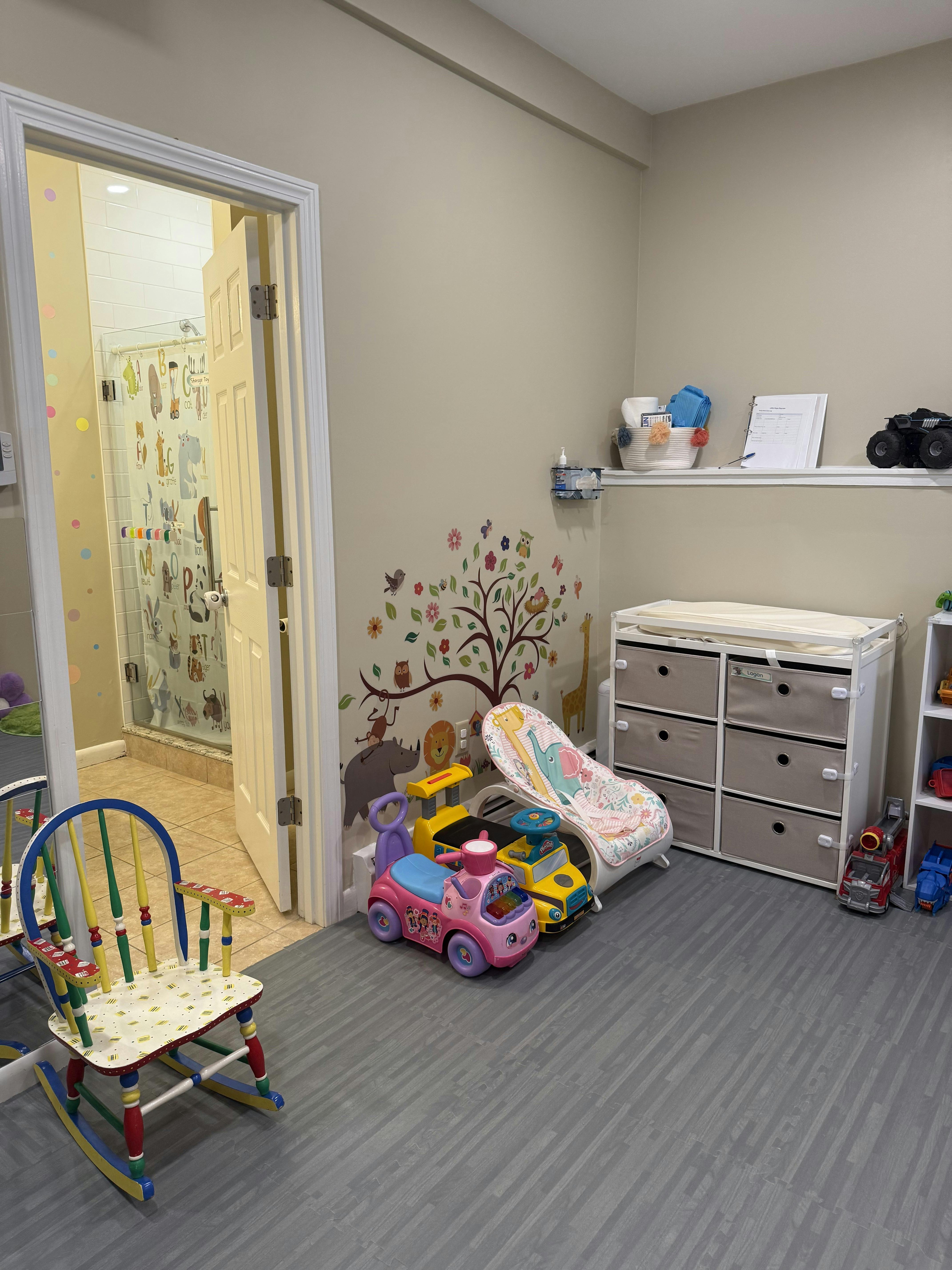 Child care room with toys, a changing table, and animal wall decals