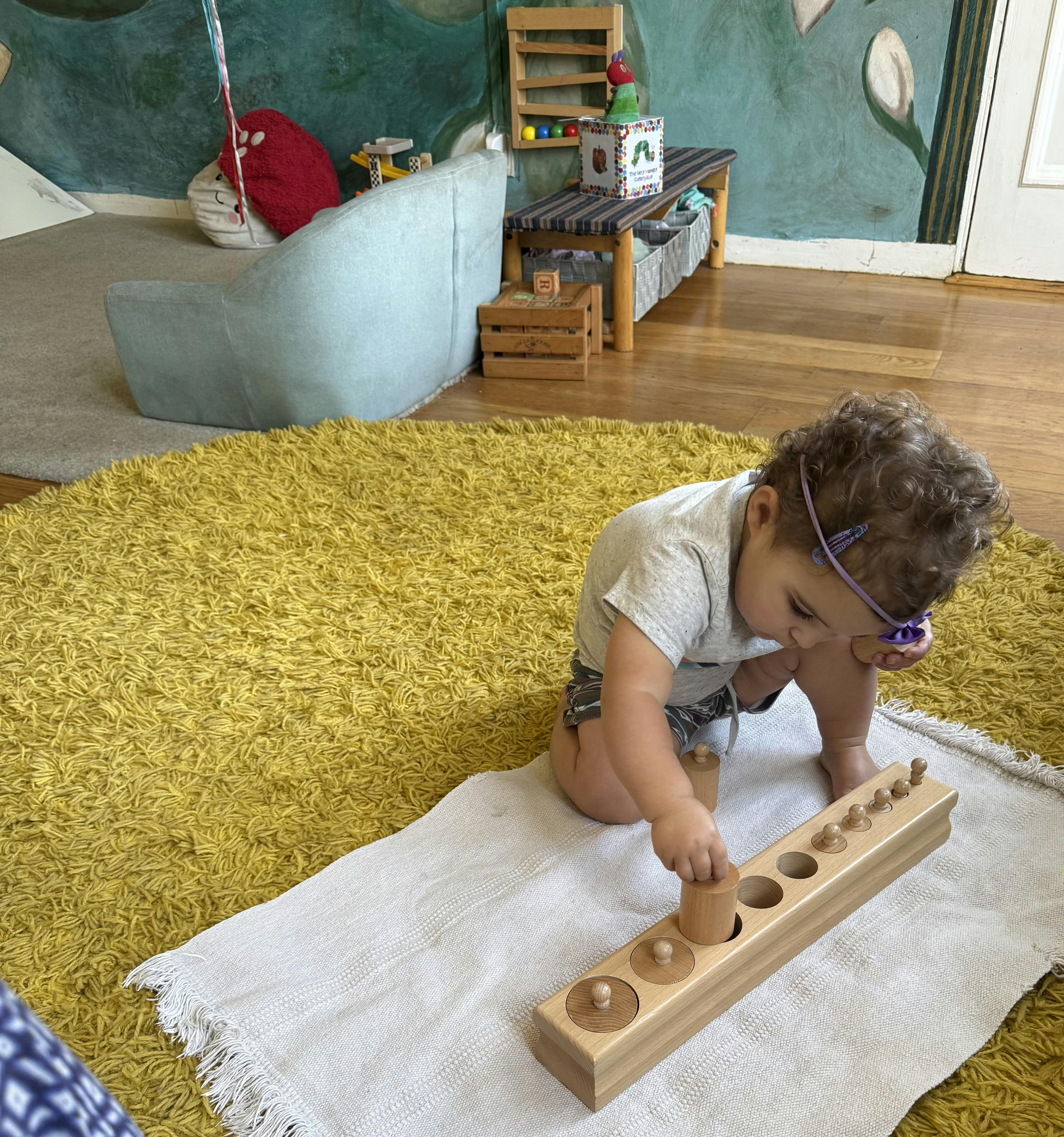 Child playing with a wooden cylinder block toy on a rug