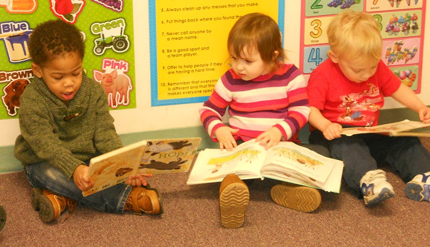 Three children sitting on the floor reading books