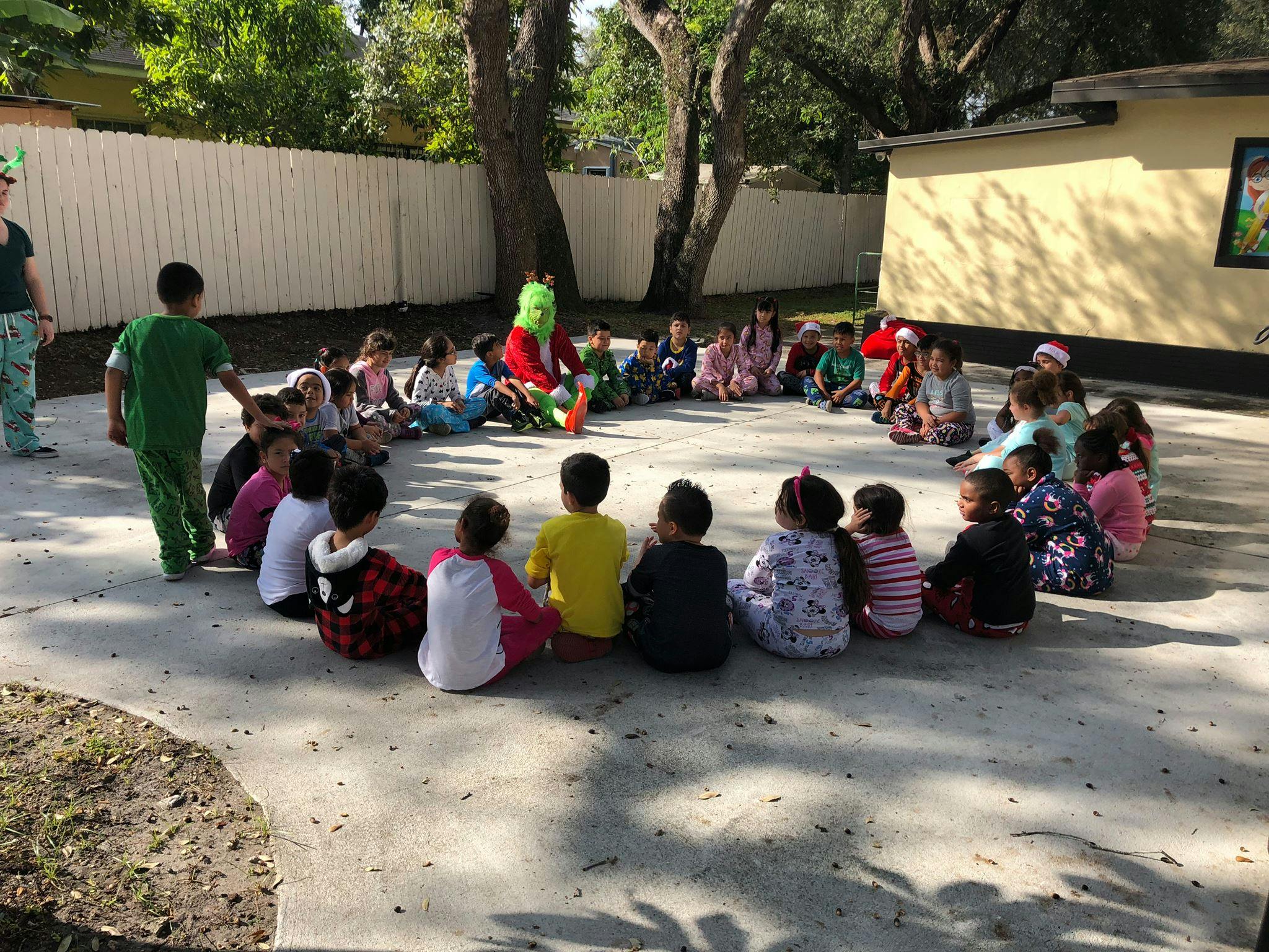 Children sitting in a circle with a person in a green costume