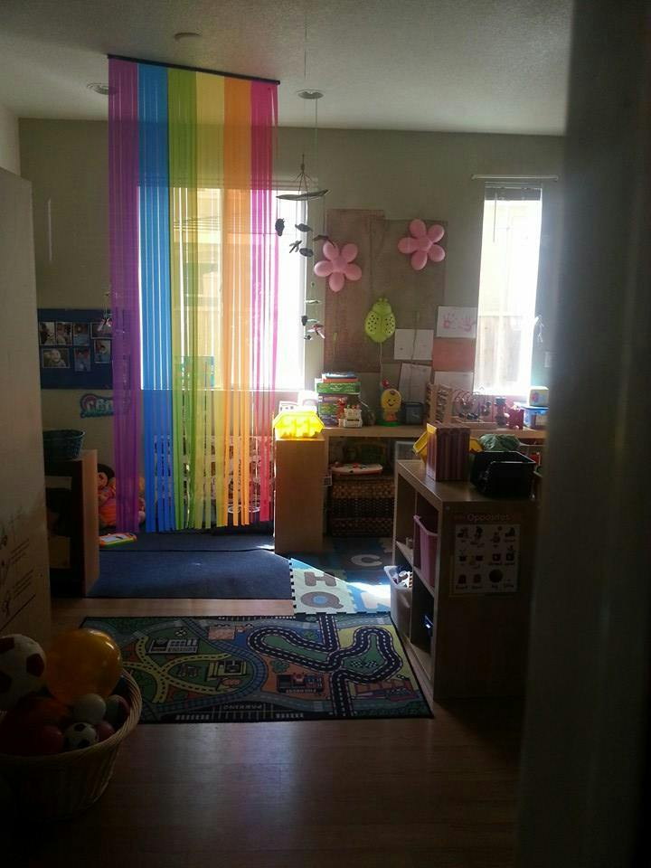 Classroom with rainbow curtain, play rug, and shelves with shelves