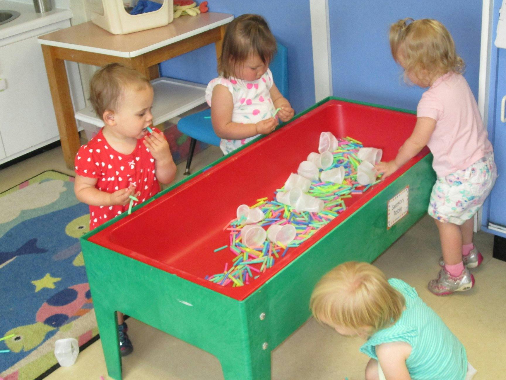 Children playing with colorful items in a sensory bin