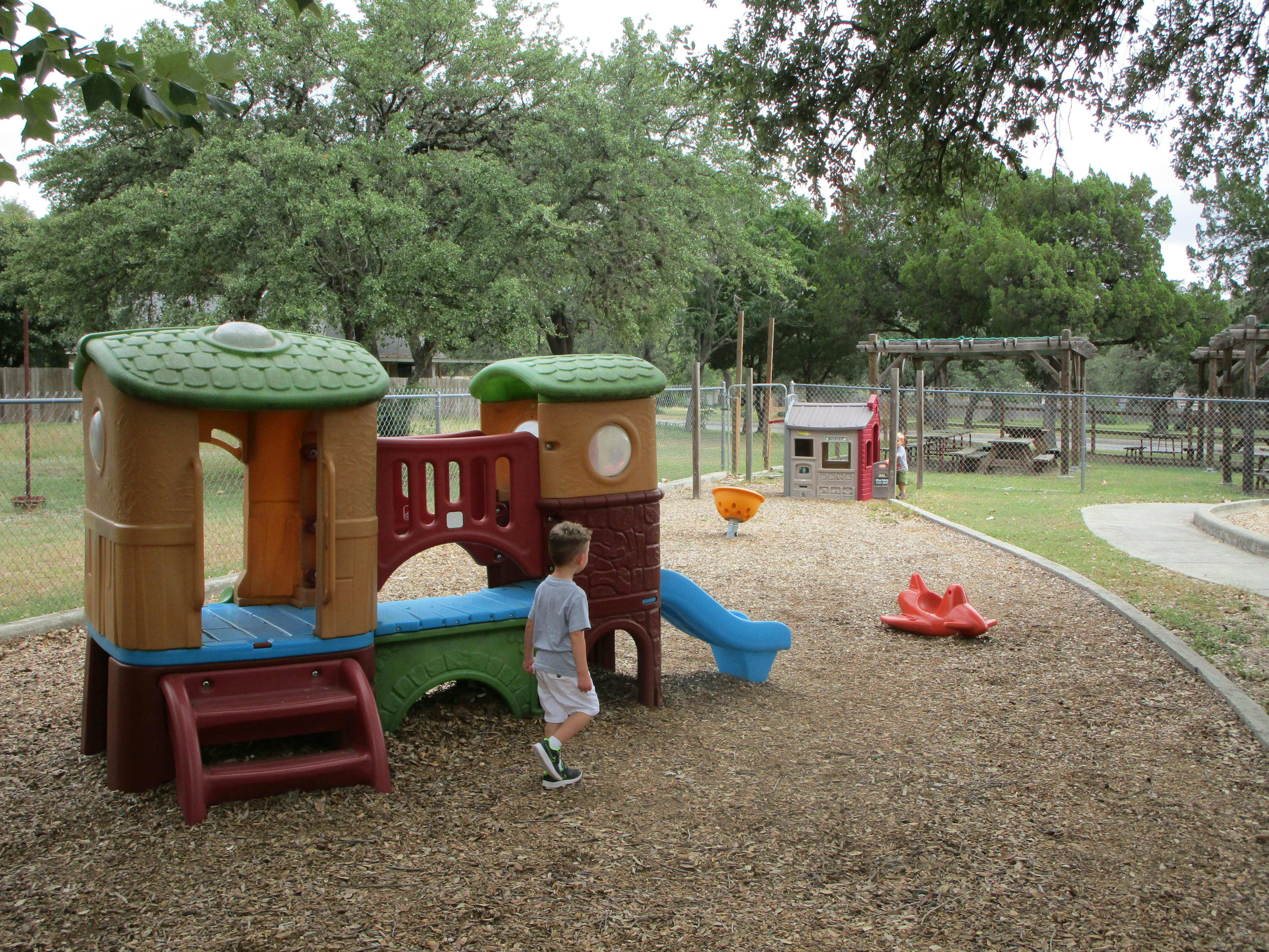 Child standing on a playground next to a play structure