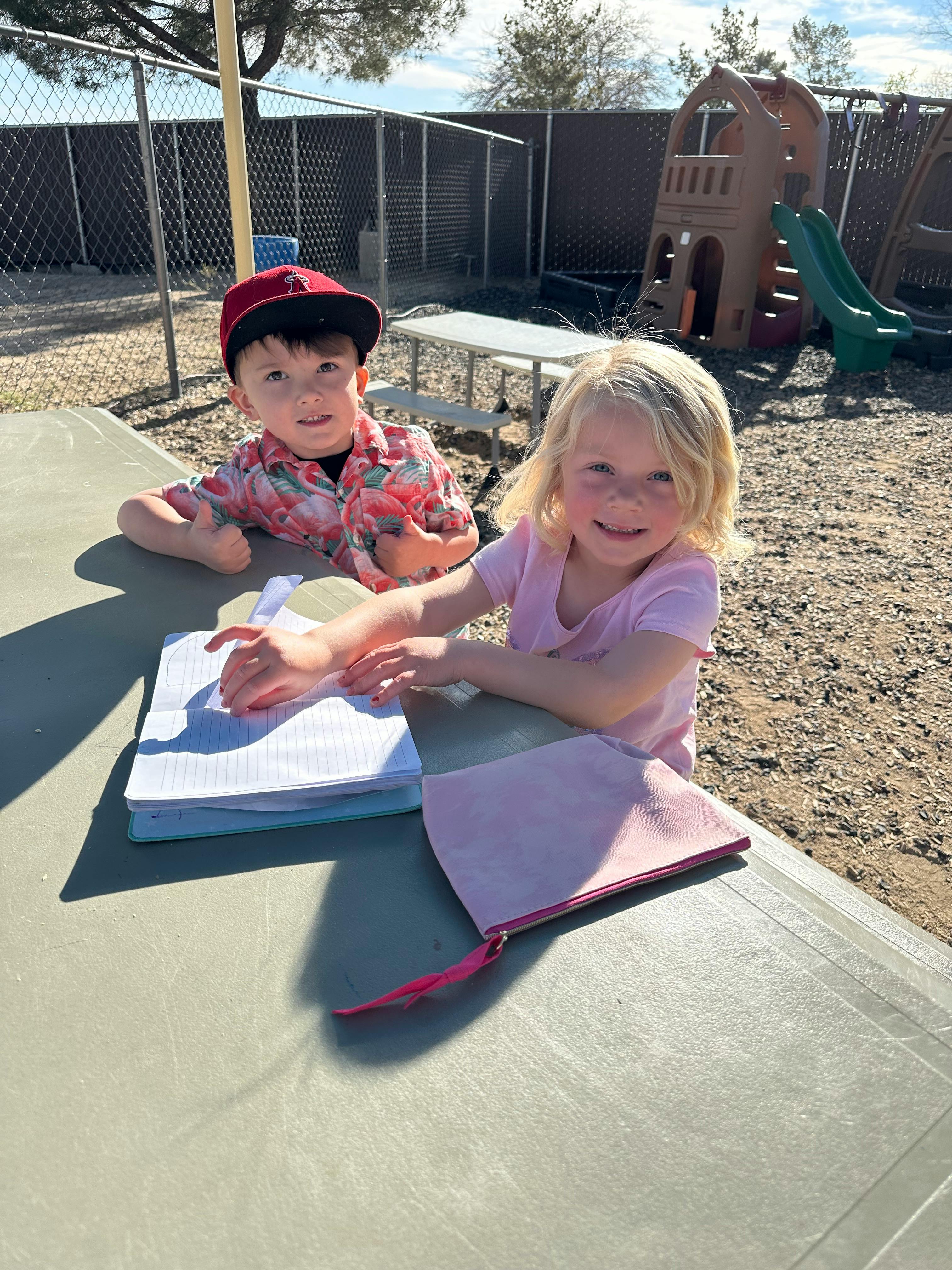 Two children sitting at a table with notebooks