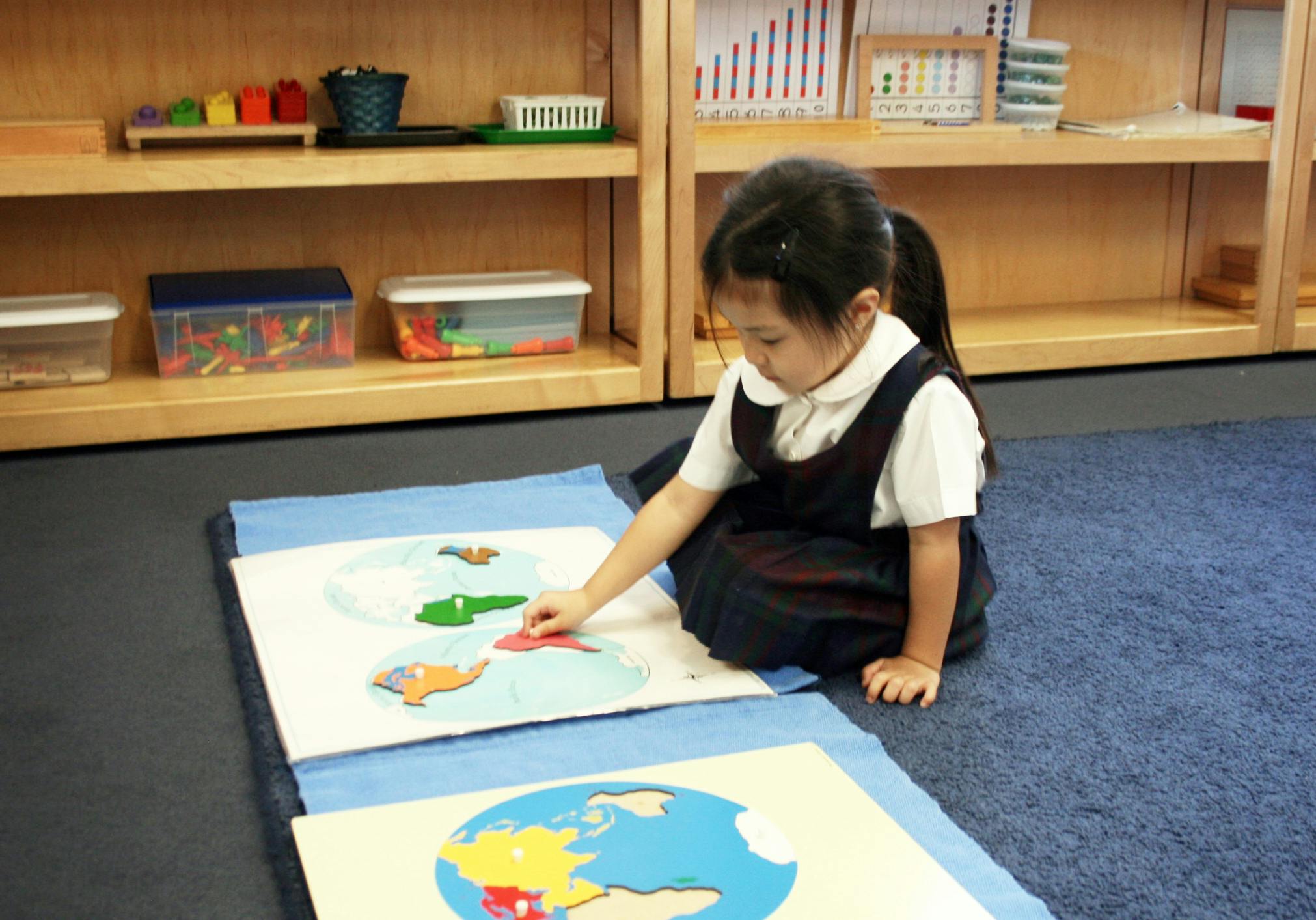 Child on floor working with a puzzle map puzzle map in a classroom
