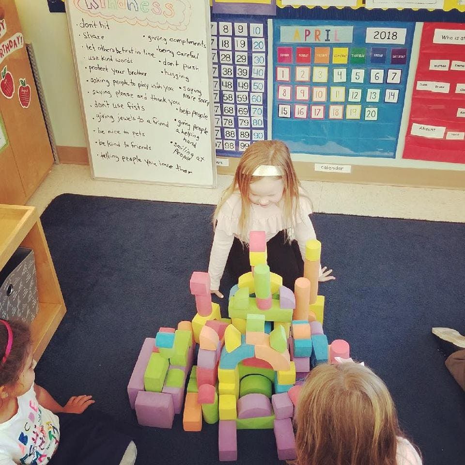 Child playing with colorful foam blocks in a classroom