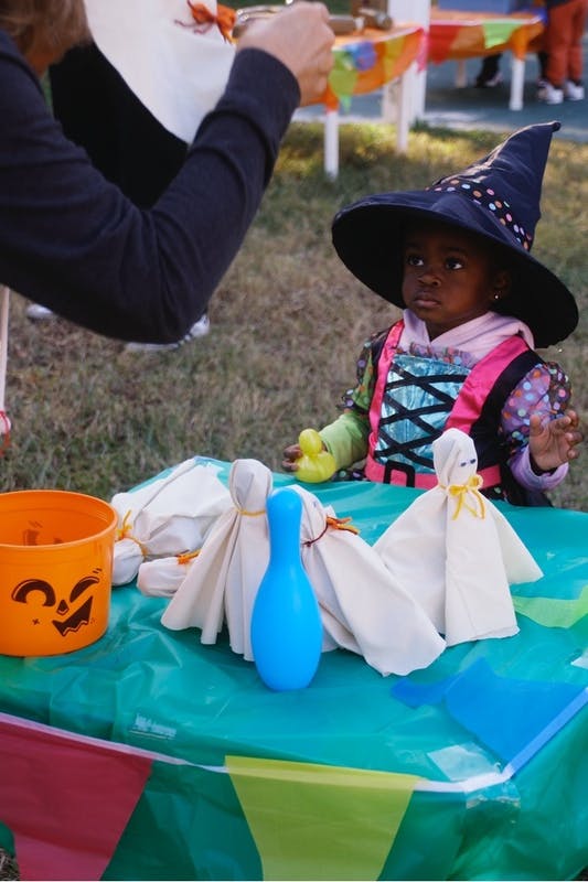 Child wearing a witch hat playing a Halloween game at a table