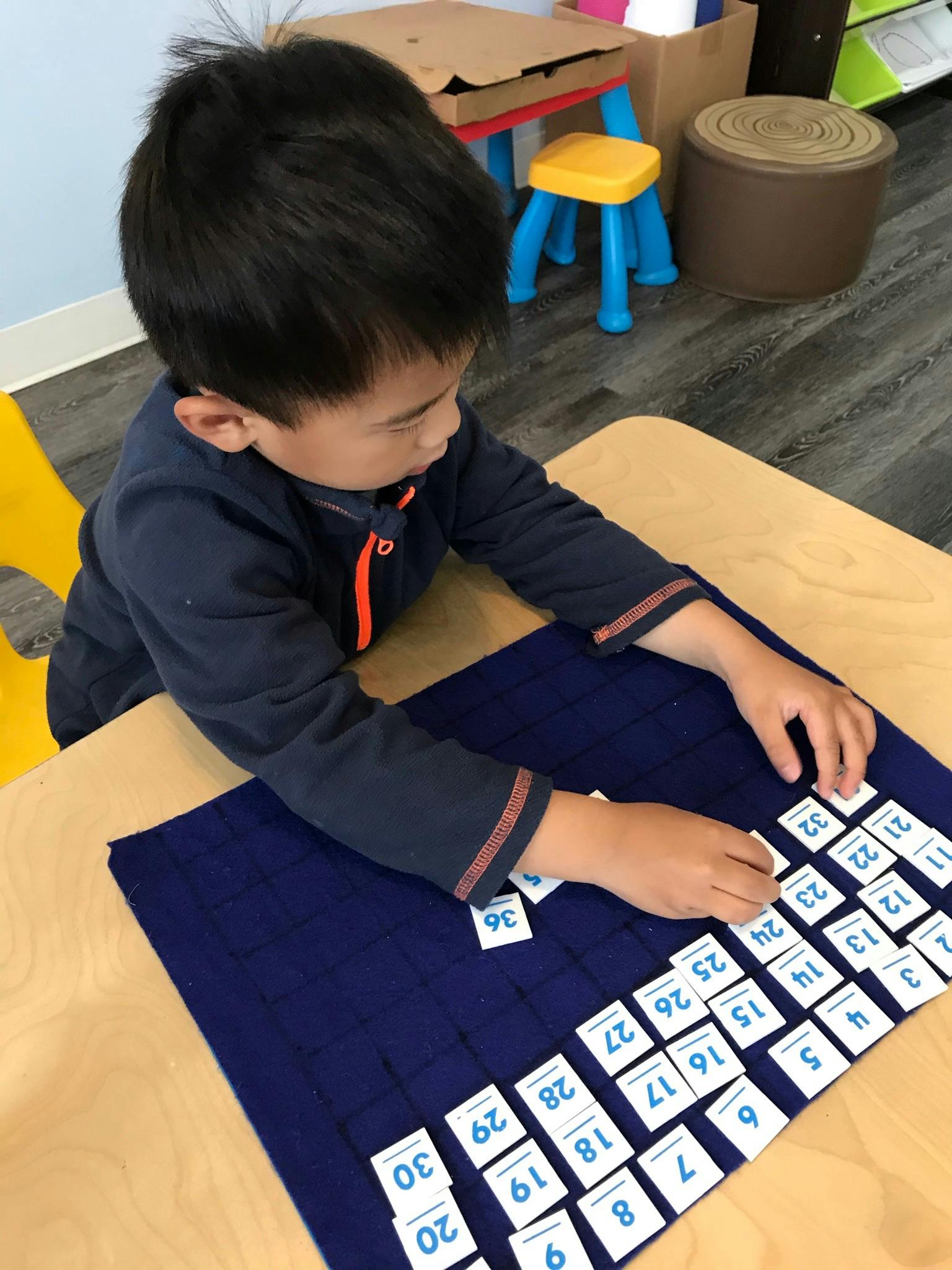 Child sorting number tiles on a blue mat