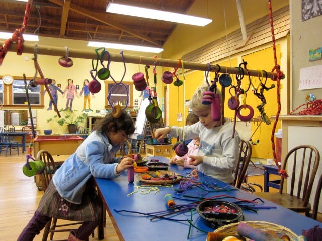 Two children crafting at a table in a classroom