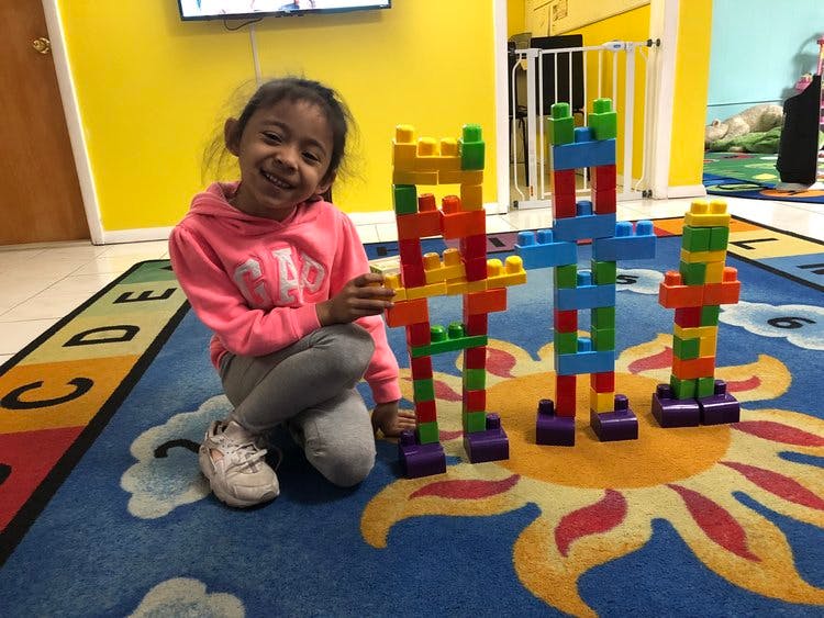 Child kneeling on a rug next to colorful building block structures