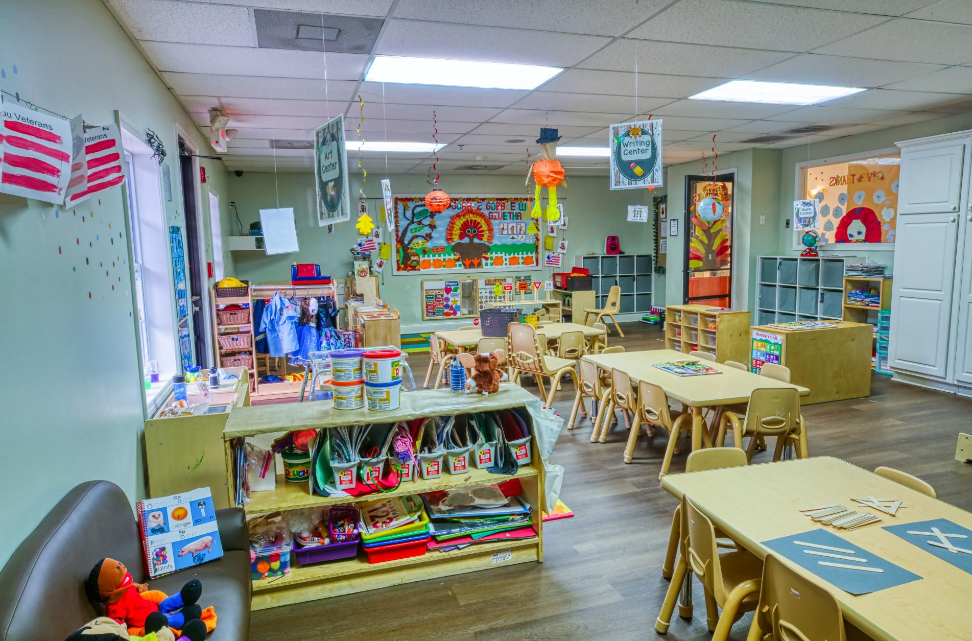 Classroom with small tables and chairs, toys, and decorations on the walls