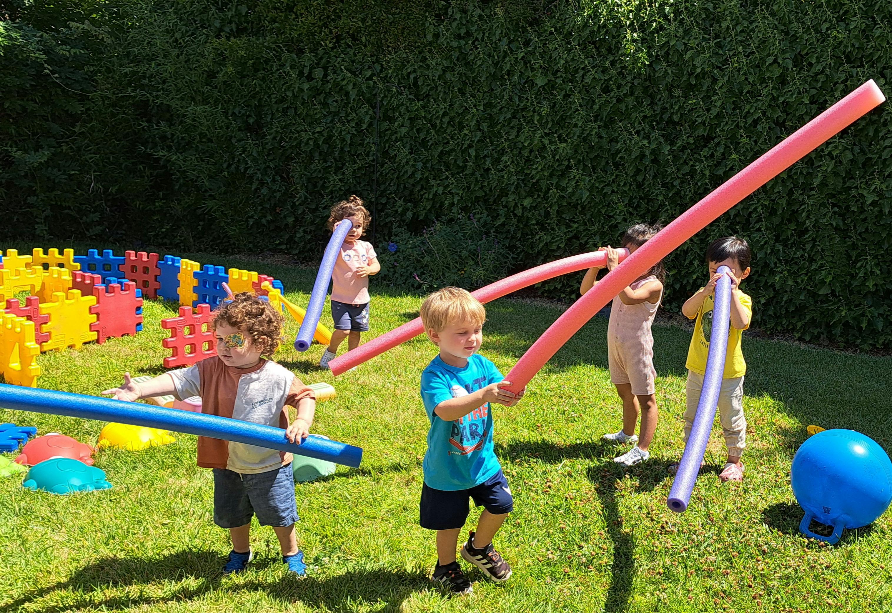 Children playing with pool noodles outdoors
