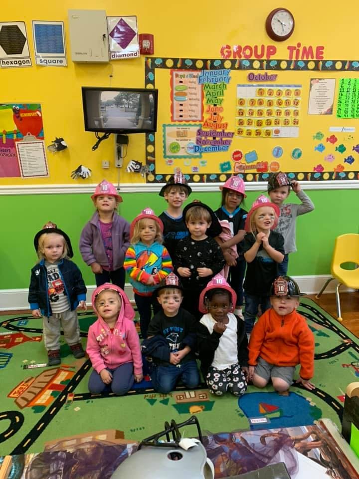 Group of children wearing firefighter hats in a classroom