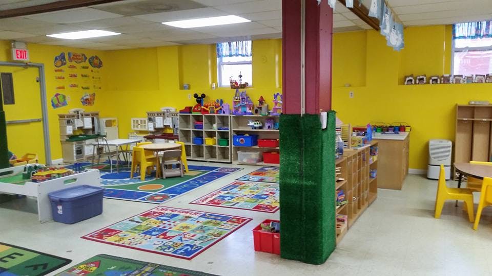 Empty classroom with yellow walls, colorful rugs, and small tables