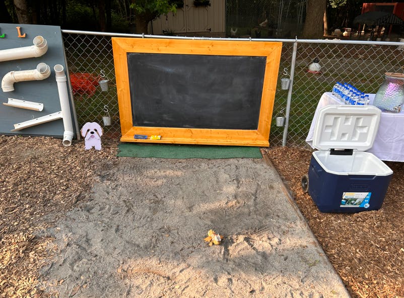 Outdoor chalkboard with a sand pit in front of it