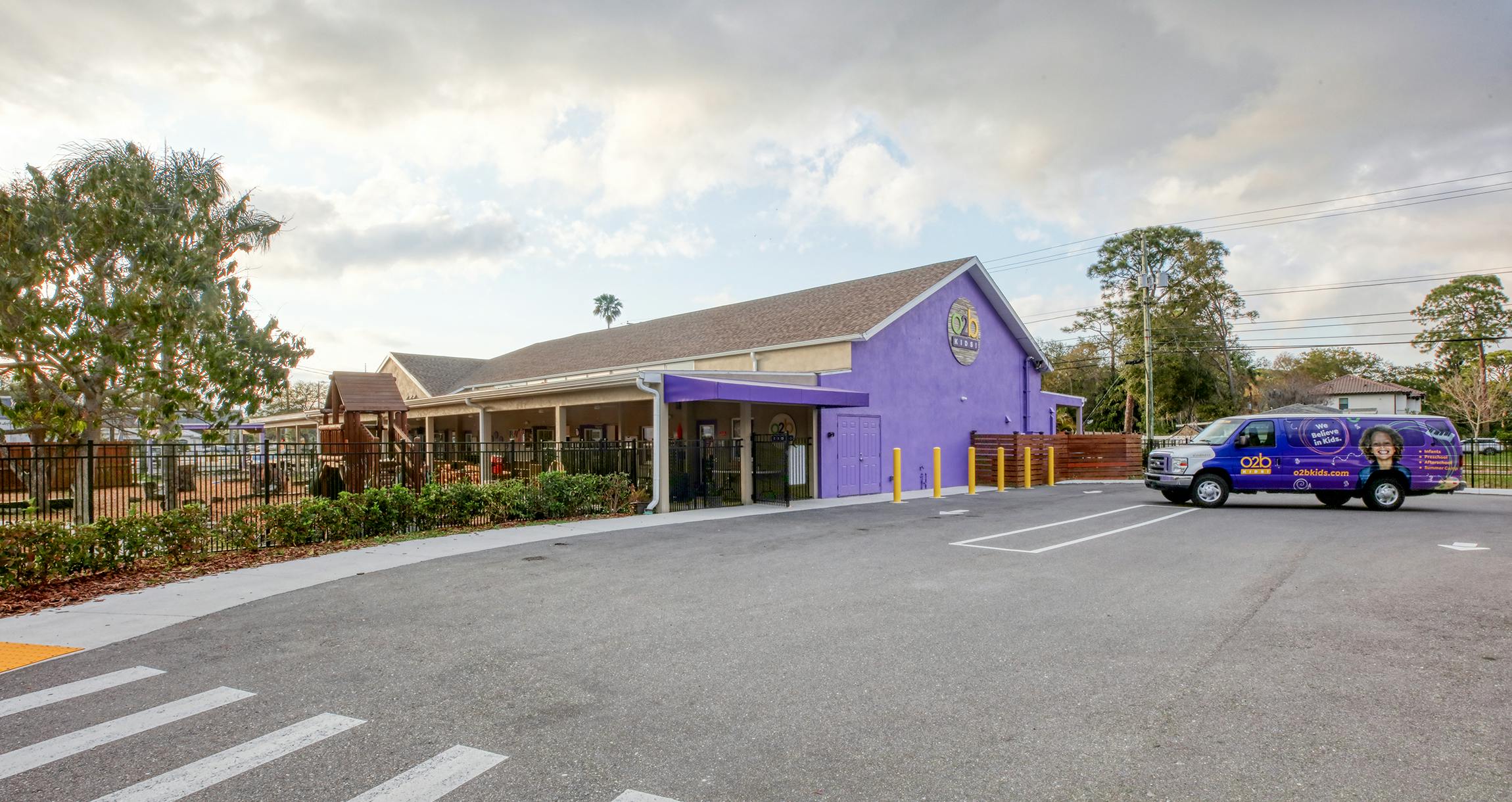 Purple building with a playground and a branded van in a parking lot
