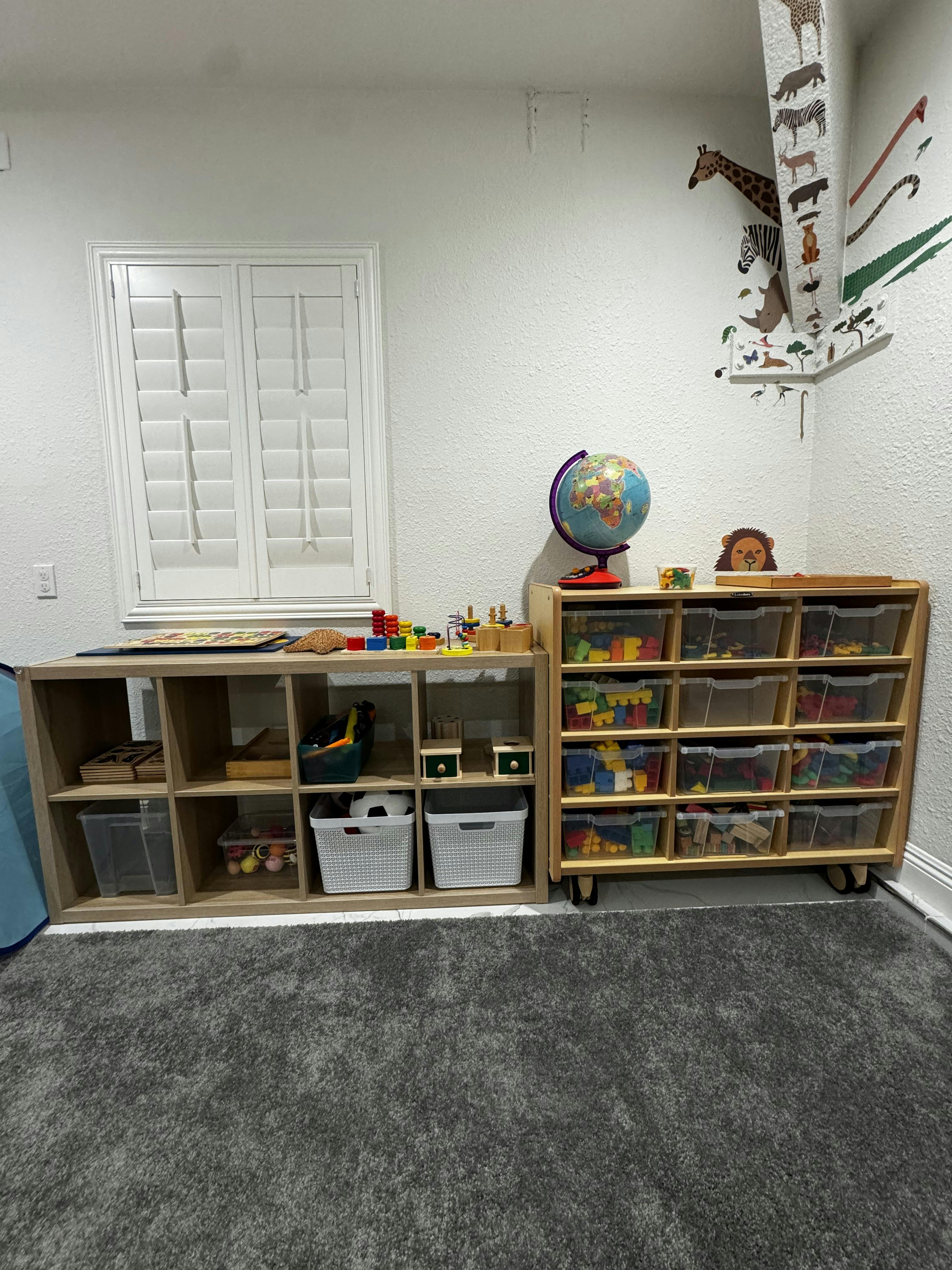 Classroom with wooden shelves filled with toys and a globe