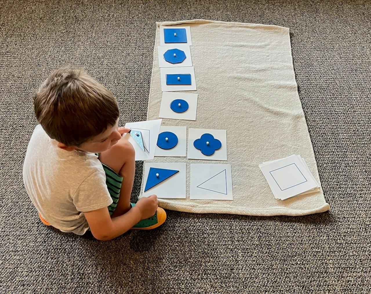 Child playing with shape matching game on a mat