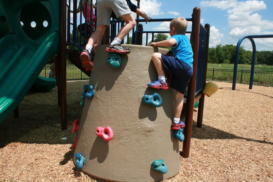 Two children climbing on a playground structure