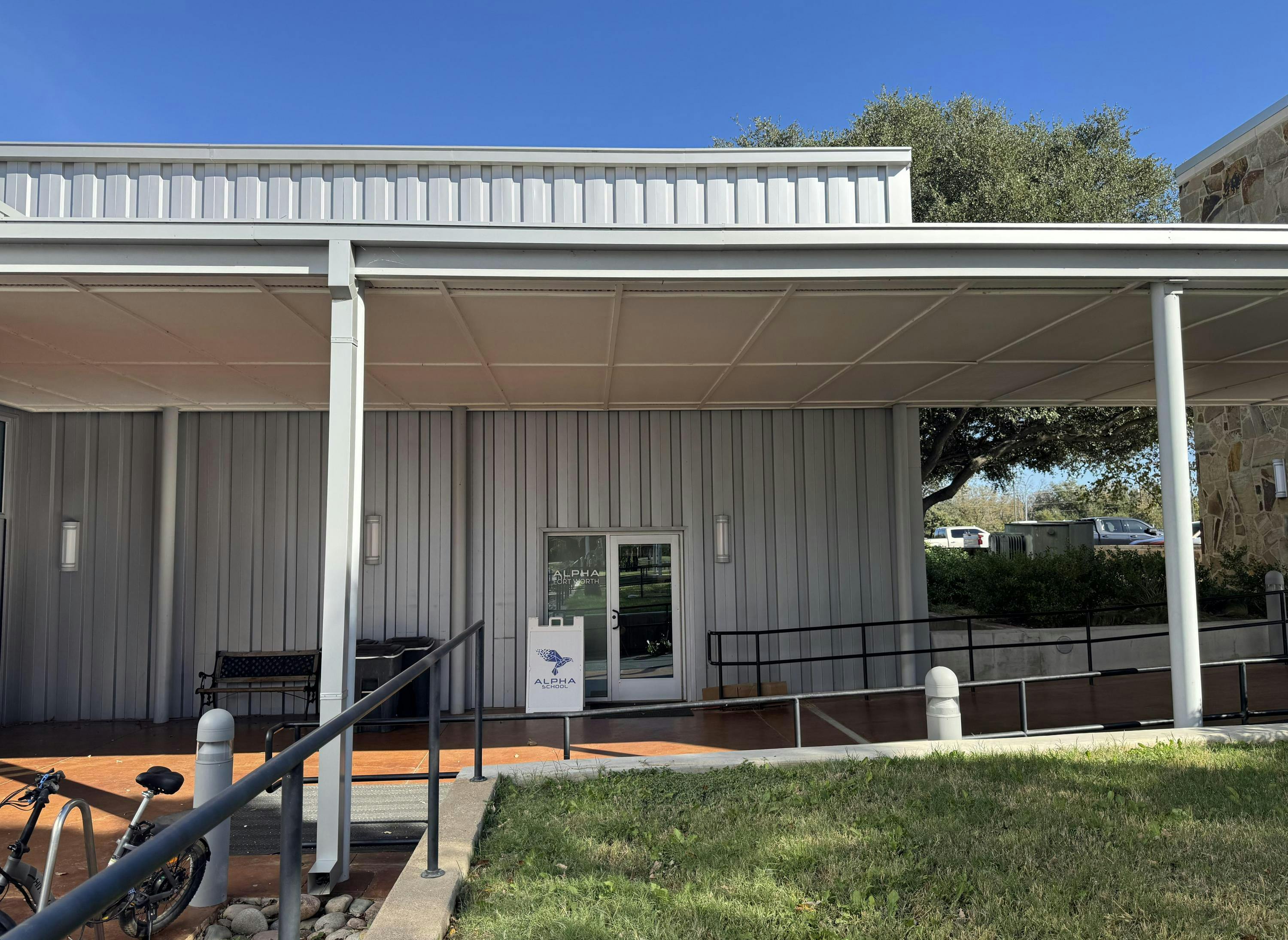 Building exterior with a covered walkway and a sign for Alpha School
