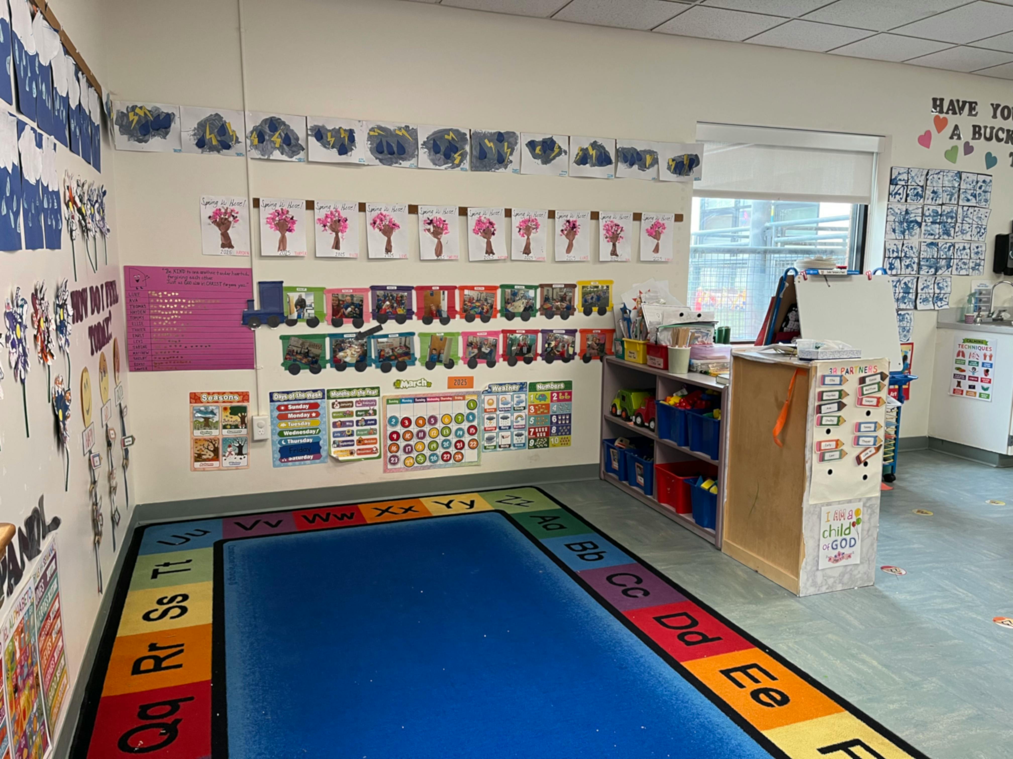 Classroom with colorful rug and children's artwork on the walls