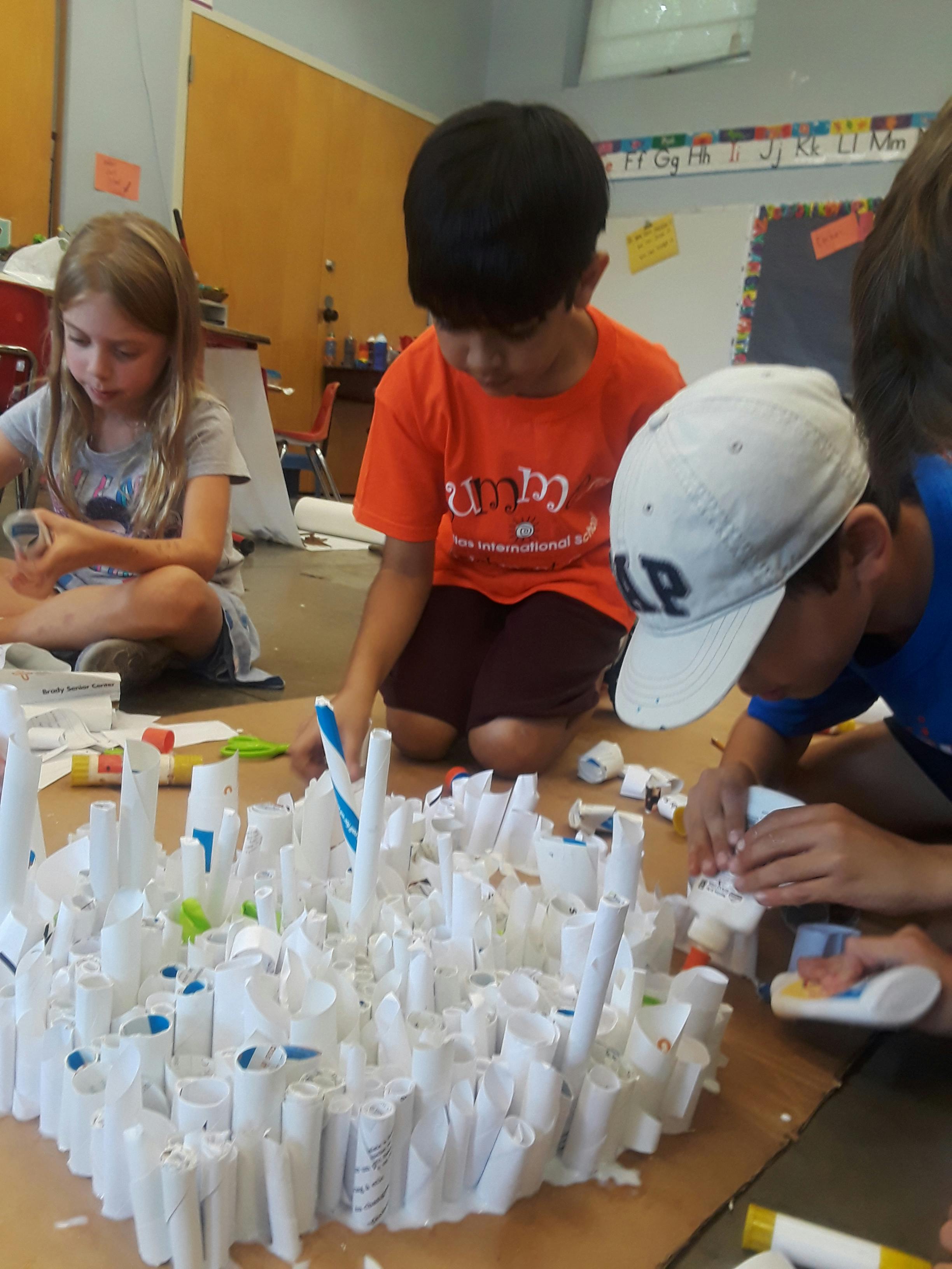 Children creating a craft project with rolled paper tubes